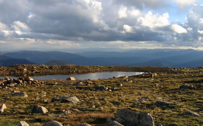 Mountain landscape with a small lake and cloudy sky