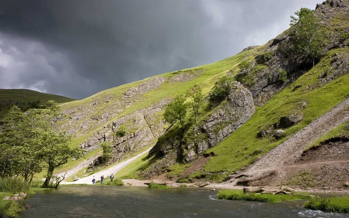 People walking by a river in a rocky valley