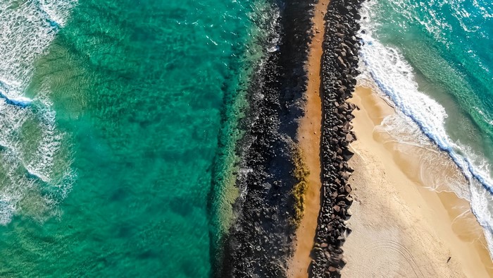 Aerial view of a rocky breakwater and ocean waves