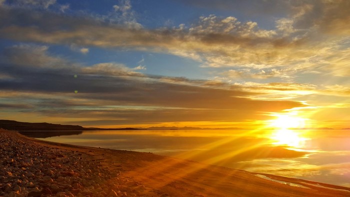 Sunset over a calm lake with rocky shore