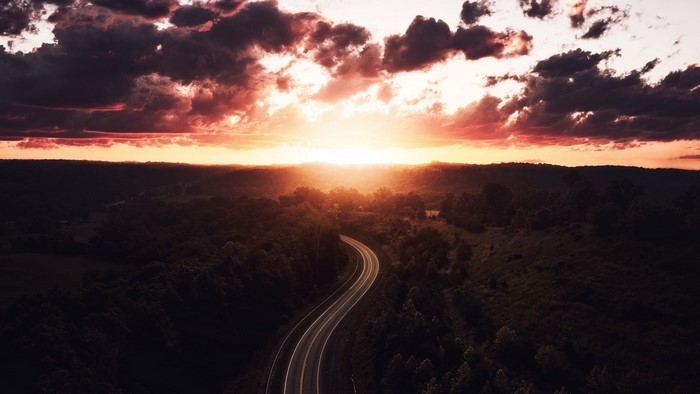 Road to sunset over rolling hills
