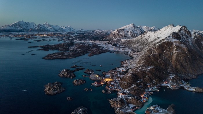 Aerial view of a Norwegian coastal village with snow-capped mountains