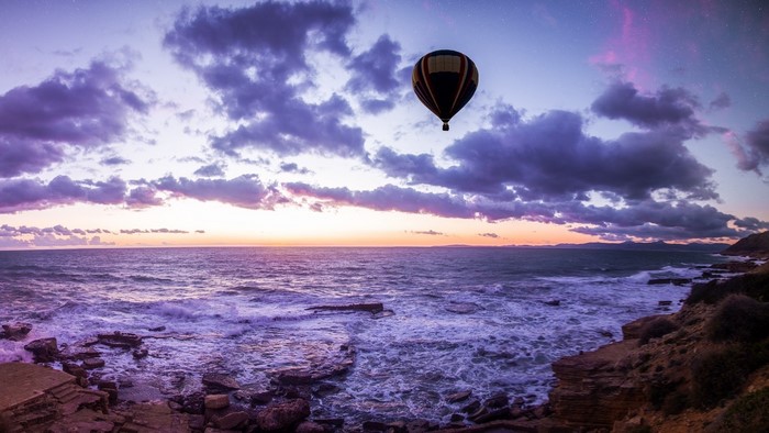 Hot air balloon over the ocean at sunset