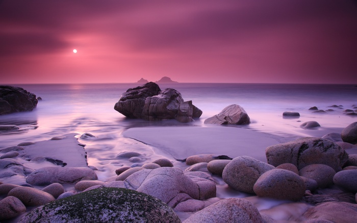 Sunset over rocky beach at Porth Nanven