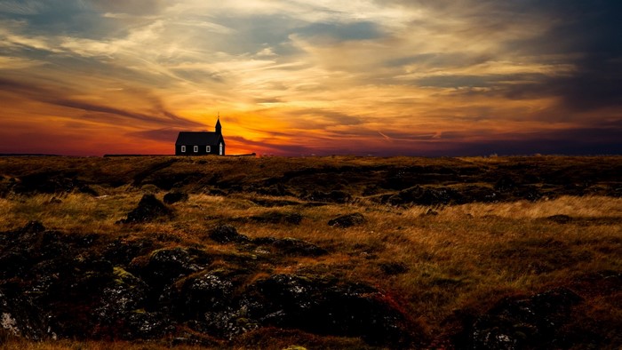Black church on a hill at sunset