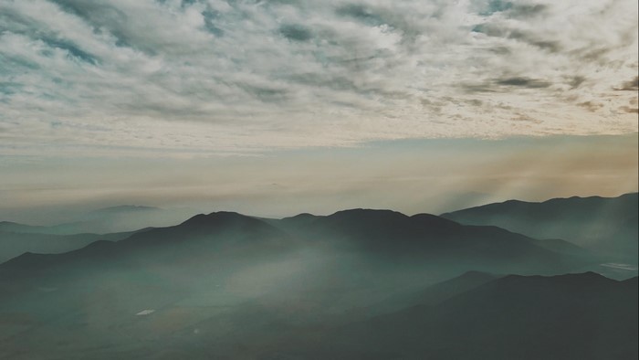 Mountain range shrouded in fog with sunbeams