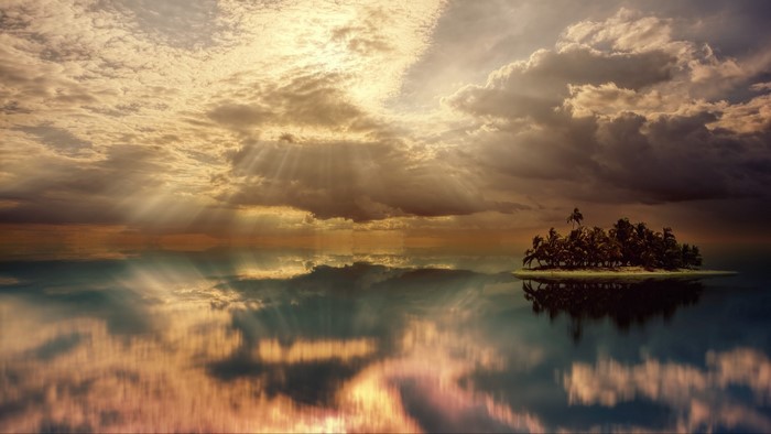 Island with palm trees in the ocean under cloudy sky