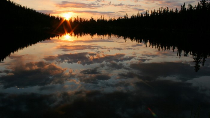 Sunset over a forest lake with reflections