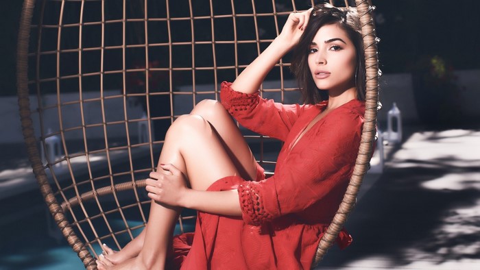 Olivia Culpo in a red dress sitting in a chair