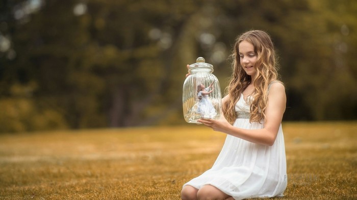 Girl holding a glass jar with a miniature dancer inside