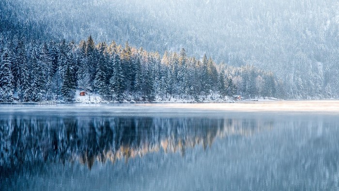 Winter lake with snow-covered forest and reflection