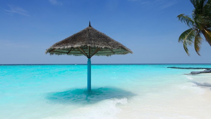 Thatched umbrella in turquoise ocean water