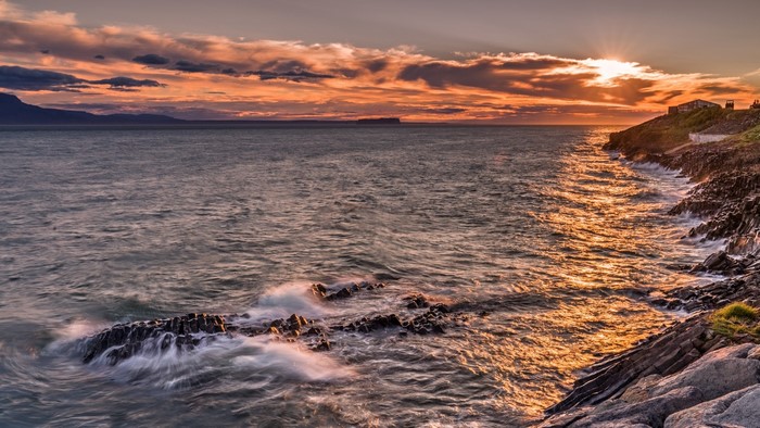 Sunset over the ocean with rocky coastline