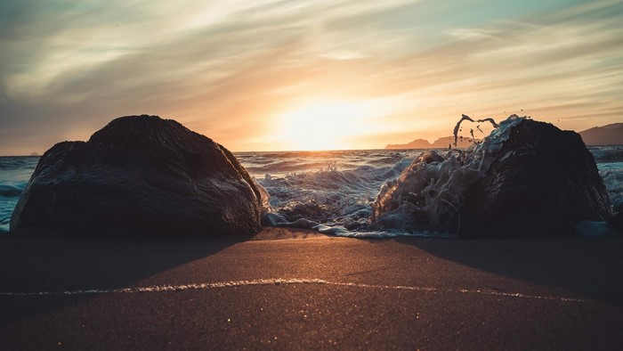Waves crashing on rocks at sunset