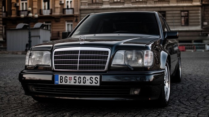 Black Mercedes-Benz E-Class W124 on cobblestone street