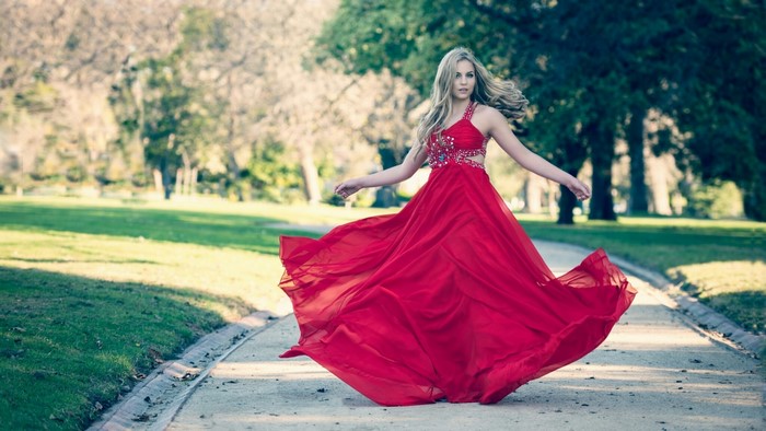 Woman in red dress twirling in a park