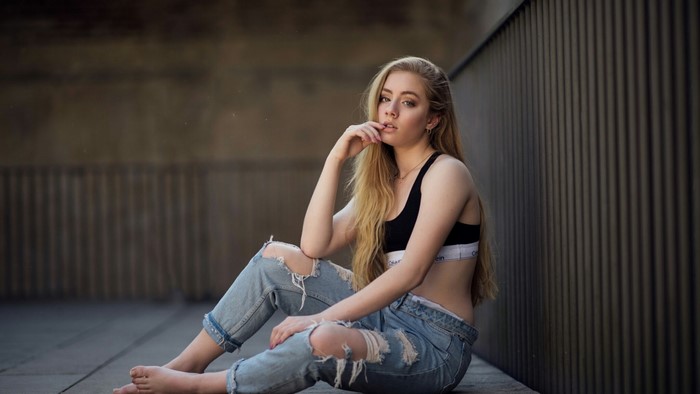 Young woman in ripped jeans and sports bra
