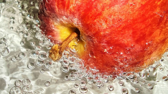 Close-up of a red apple in water with bubbles