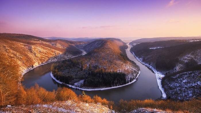 River bend in a snowy forest at sunset