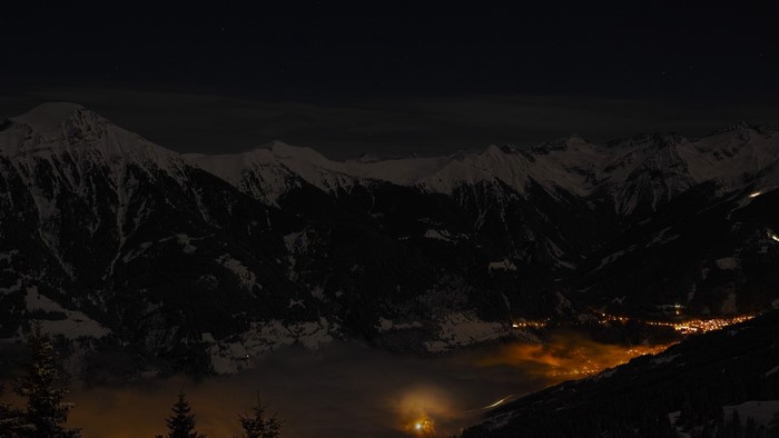 Snowy mountains at night with a village below