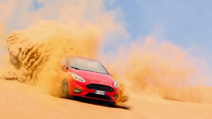 Red Ford Fiesta driving through sand dunes