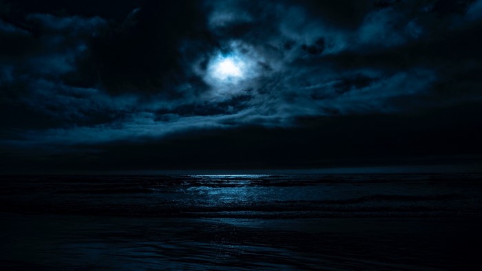 Moonlit Ocean Waves Under Cloudy Night Sky