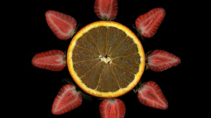 Orange slice and strawberries arranged in a sun shape