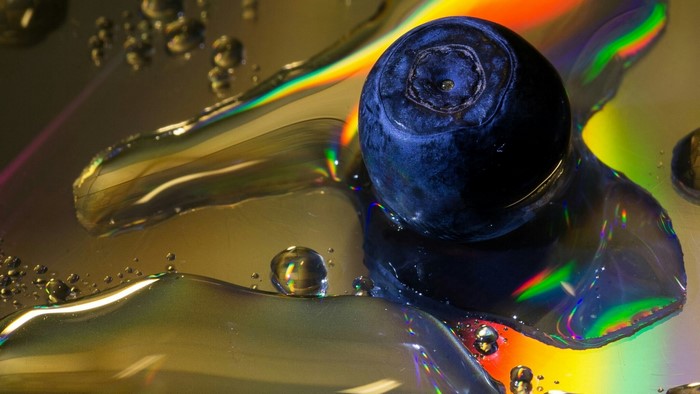 Blueberry on a reflective surface with water droplets