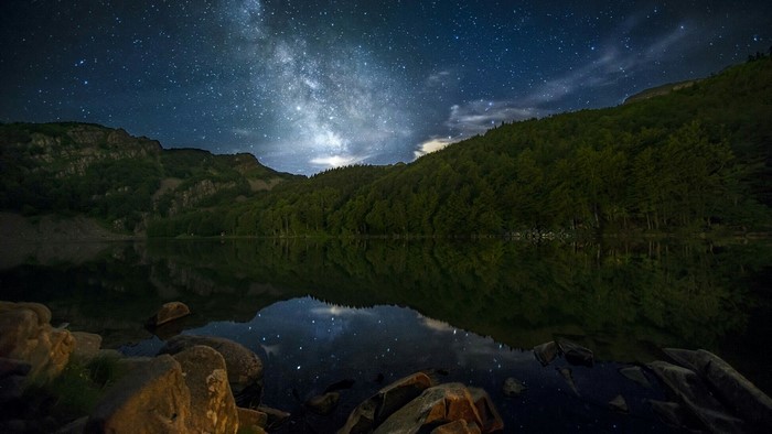 Milky Way over a forest lake at night