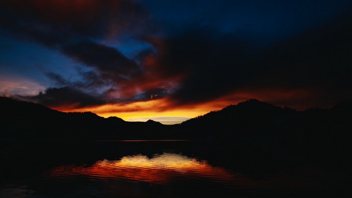 Sunset over a lake with silhouetted mountains