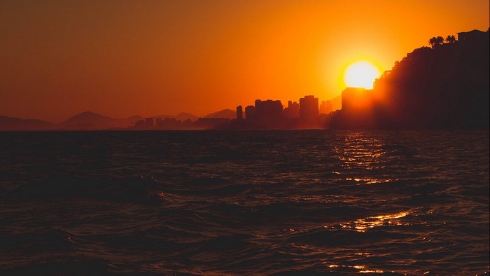 Sunset over ocean with city skyline