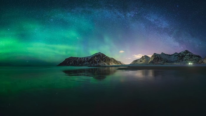 Aurora Borealis over snow-capped mountains and ocean