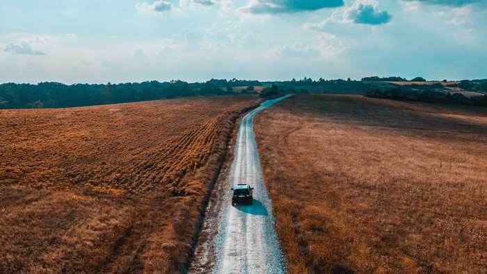 Car driving on a dirt road through fields