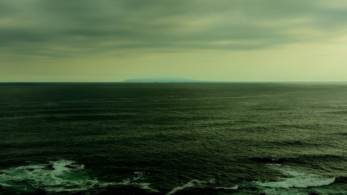 Ocean horizon with distant island and ships