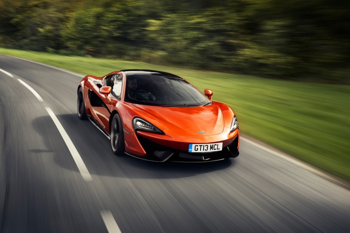 Orange McLaren 570GT driving on a road