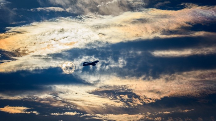 Airplane flying through clouds at sunset