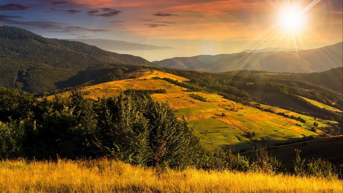 Sunlit Mountain Valley with Hay Bales