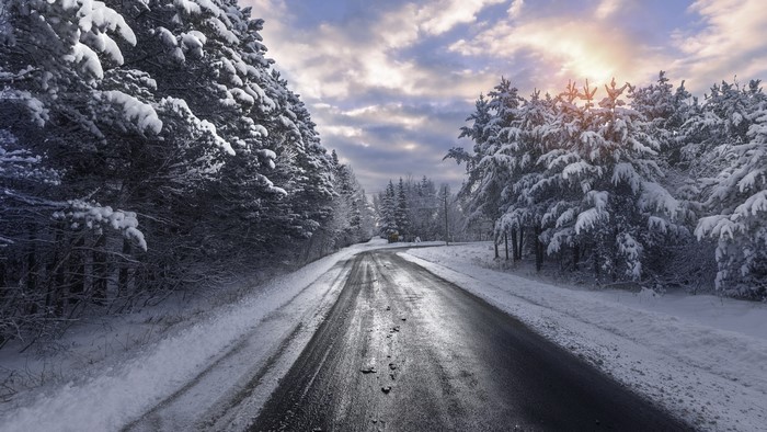 Snowy Forest Road with Sunlit Clouds