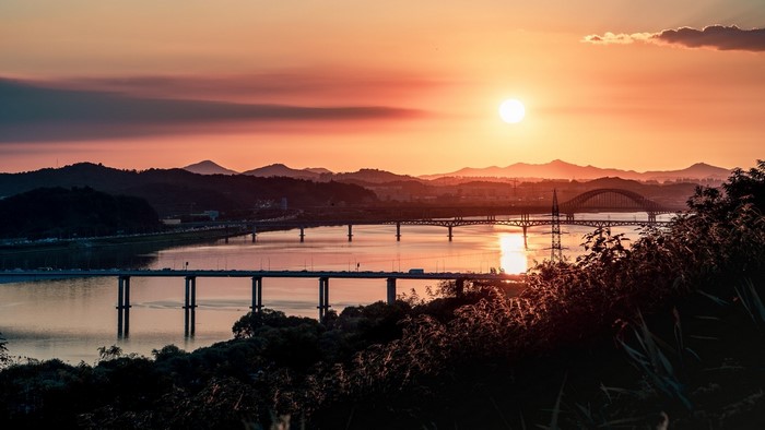 Sunset over river with bridges and mountains