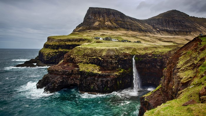 Waterfall cascading into the ocean near a village in the Faroe Islands