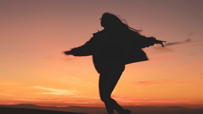 Silhouette of a person dancing at sunset