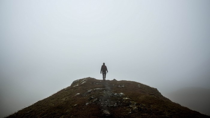 Person walking on a foggy mountain peak