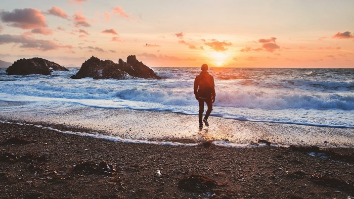 Man walking on beach at sunset