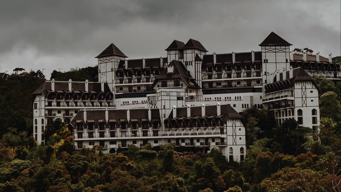 Large white hotel with dark roofs on a hill