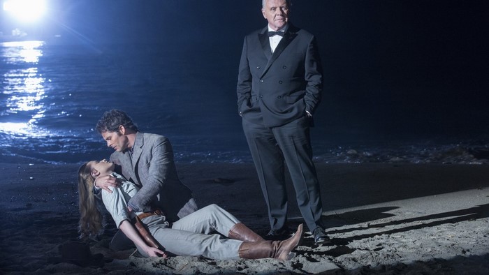 Man holding woman on beach with man in tuxedo
