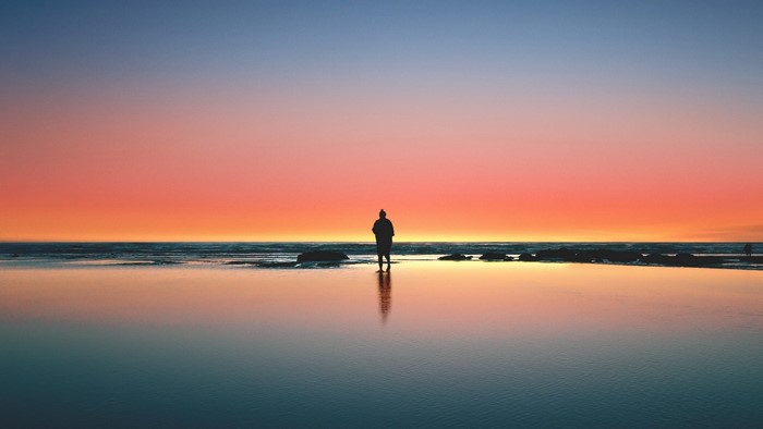 Person standing on a beach at sunset