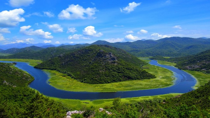 Meandering River Through Green Mountains Under Blue Sky