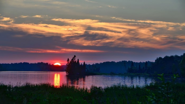 Sunset over a lake with trees and clouds