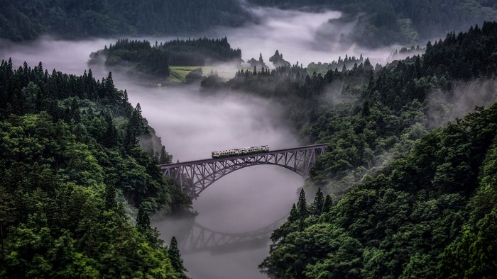 Train crossing a bridge in foggy mountains of Japan