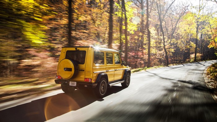 Yellow Mercedes Benz G-Wagon driving on a road